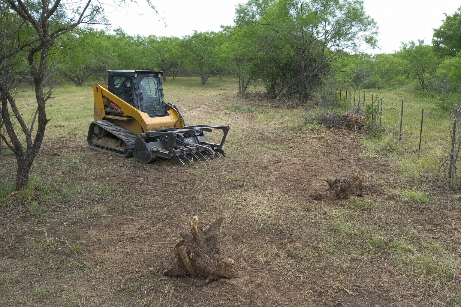 Pulled root crowns sit near the fence and lowered root rake.