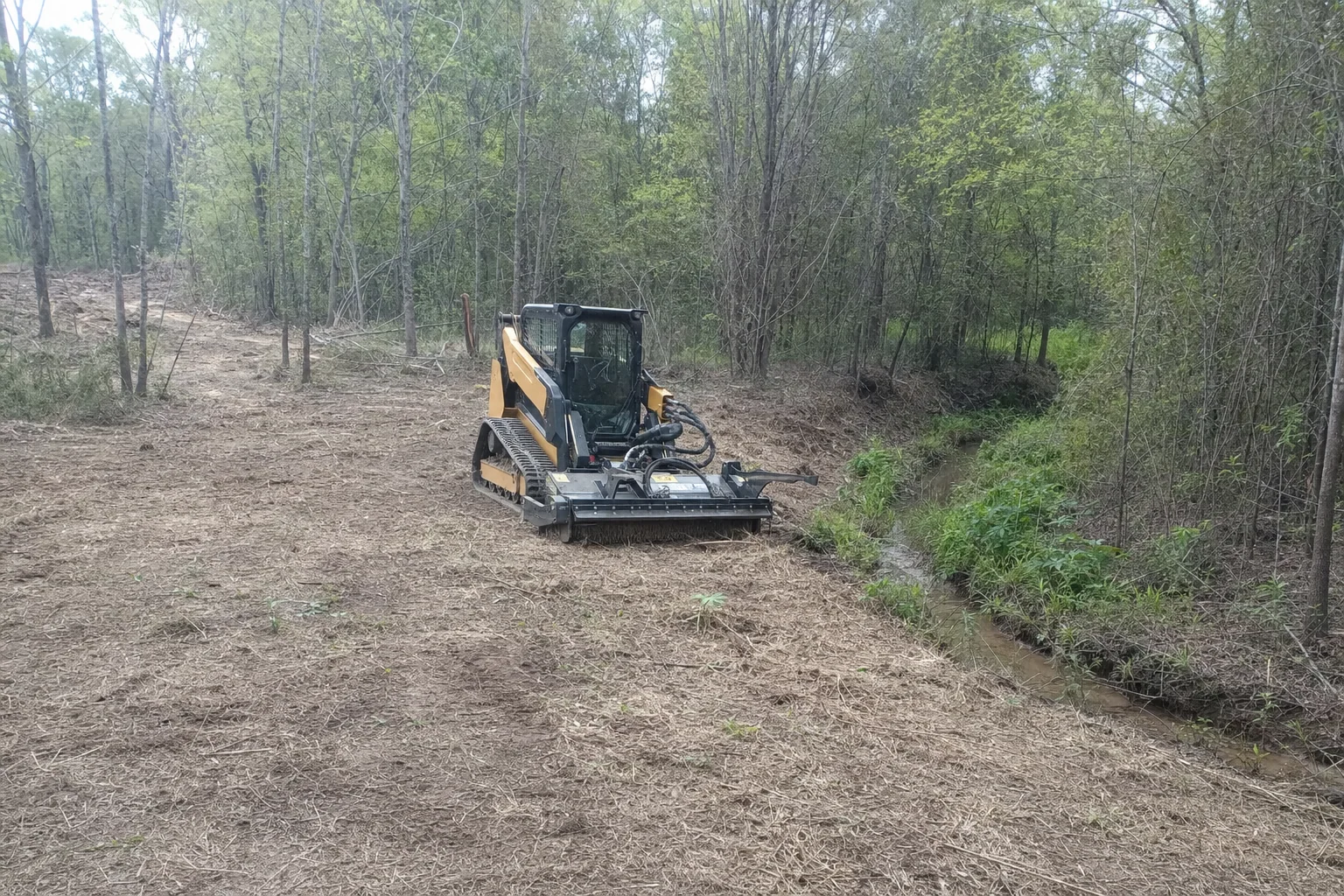 Water runs in the grassy channel beside the cleared access lane.